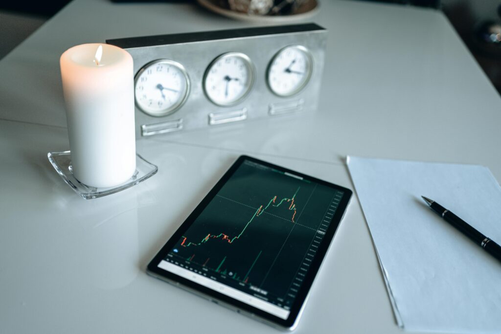 Minimalist desk setup with tablet showing trading graph alongside candle and clocks.