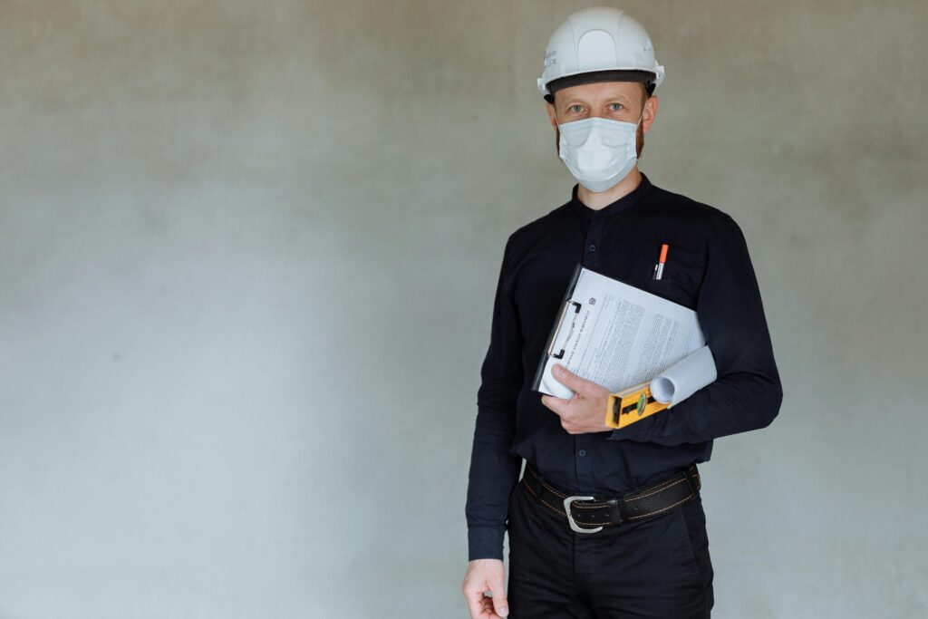 Construction worker wearing safety gear and holding documents during pandemic.