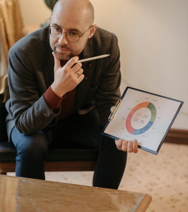 pexels-photo-6716014-6716014 A serious counselor discusses mental health using a chart on a clipboard.