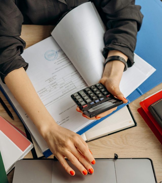 pexels-photo-8296981-8296981 A business professional uses a calculator among documents and laptop on a desk for financial tasks.